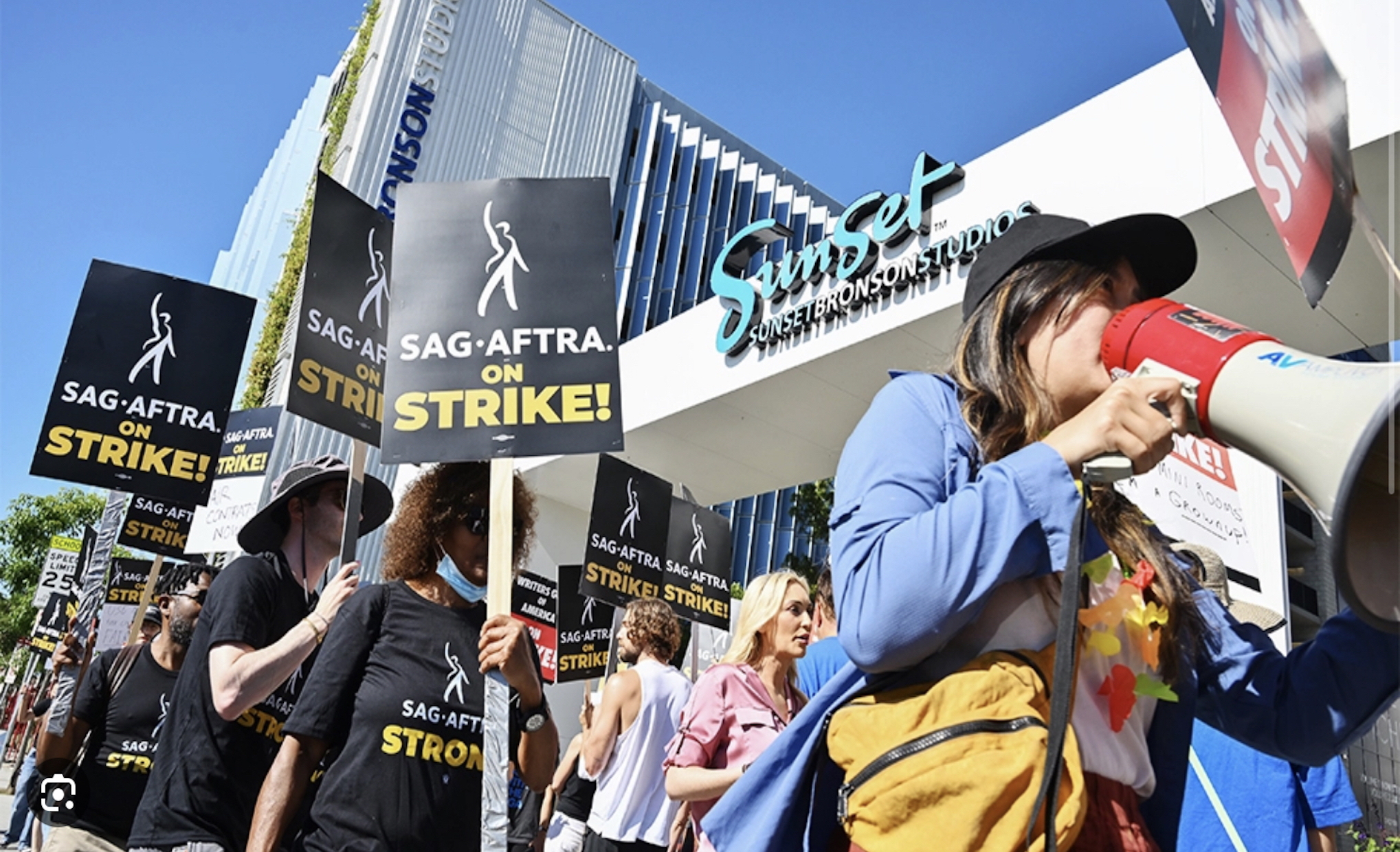 Protesters holding signs representing the unified stance of SAG-AFTRA and WGA members against AMPTP policies.